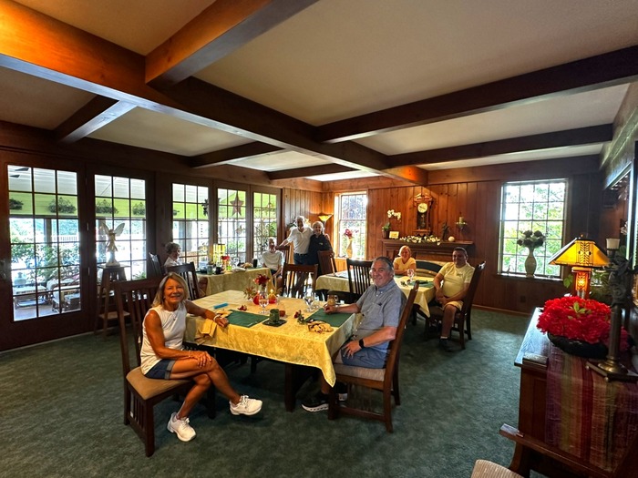Couple sitting at breakfast table at Annville Inn, glass wall behind table shows through to the Garden Room