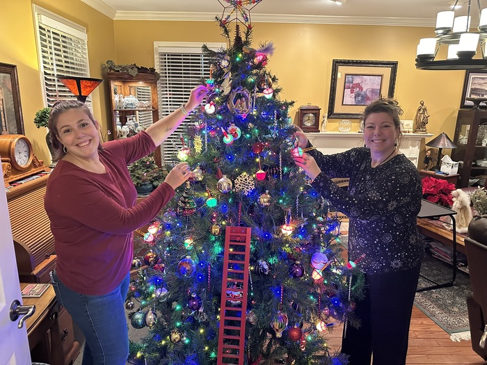 Fall scene at Annville Inn. Showing manicured lawn, sidewalk, beautiful fall trees in red and gold, a circular bench around a tree, and part of a pergola with bench under it. Annville Inn News.