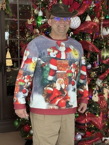 Man in cowboy hat in front of one of Annville Inn's 65 Christmas Trees! He has on a Christmas sweather.