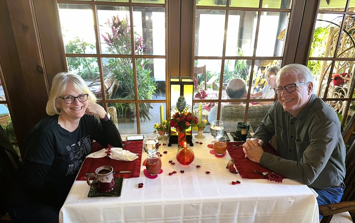 Couple sitting at breakfast table at Annville Inn, glass wall behind table shows through to the Garden Room