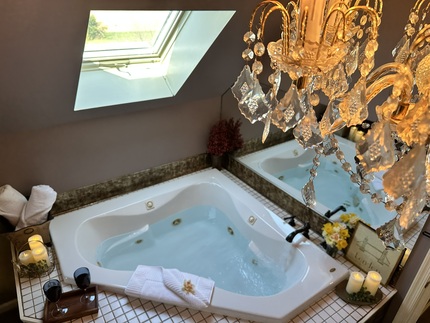The English Manor Suite's Jacuzzi, an aerial view.
Shows the Jacuzzi as well as a chandlier suspended from ceiling...shows up in top right corner. An open skylight illuminates the Jacuzzi.