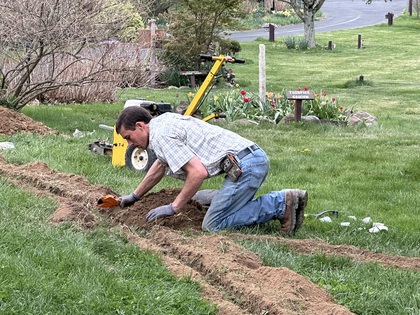 Young man on all fours, working on a trench in the ground at Annville inn.