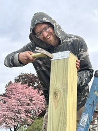 Young man up on a ladder working on a tall 6' post at Annville Inn.