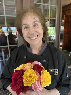 Photo of Rosalie George, Founder and Innkeeper of Annville Inn. Holding flowers from the Inn's botanical gardens.