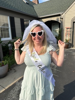 Bride standing in lane at Annville Inn, she is wearing heart shaped glasses and has a sash that says 
