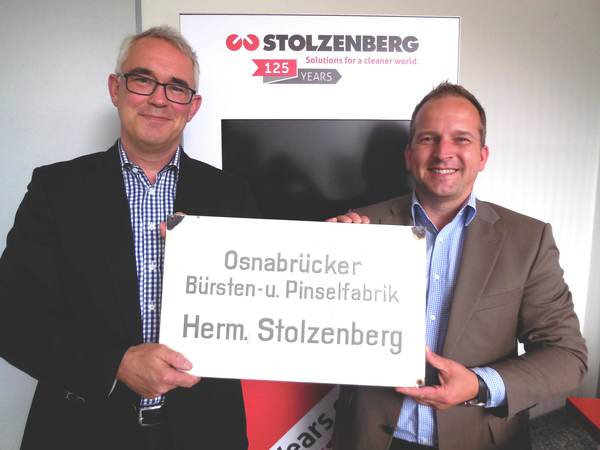 Kai Stolzenberg, Geschäftsführer und Inhaber in vierter Generation, und Michael Meisel, Leiter Vertrieb Eigenmarke Deutschland, präsentieren das Firmenschild, mit dem alles angefangen hat.