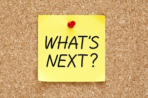 IMAGE: A yellow post-it note is pinned to a corkboard. It has letters which spell out What's Next?.